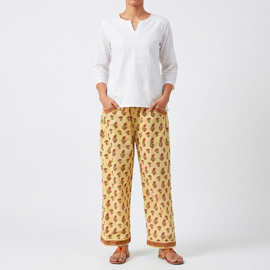 Person wearing a white top and yellow patterned pants on a white background
