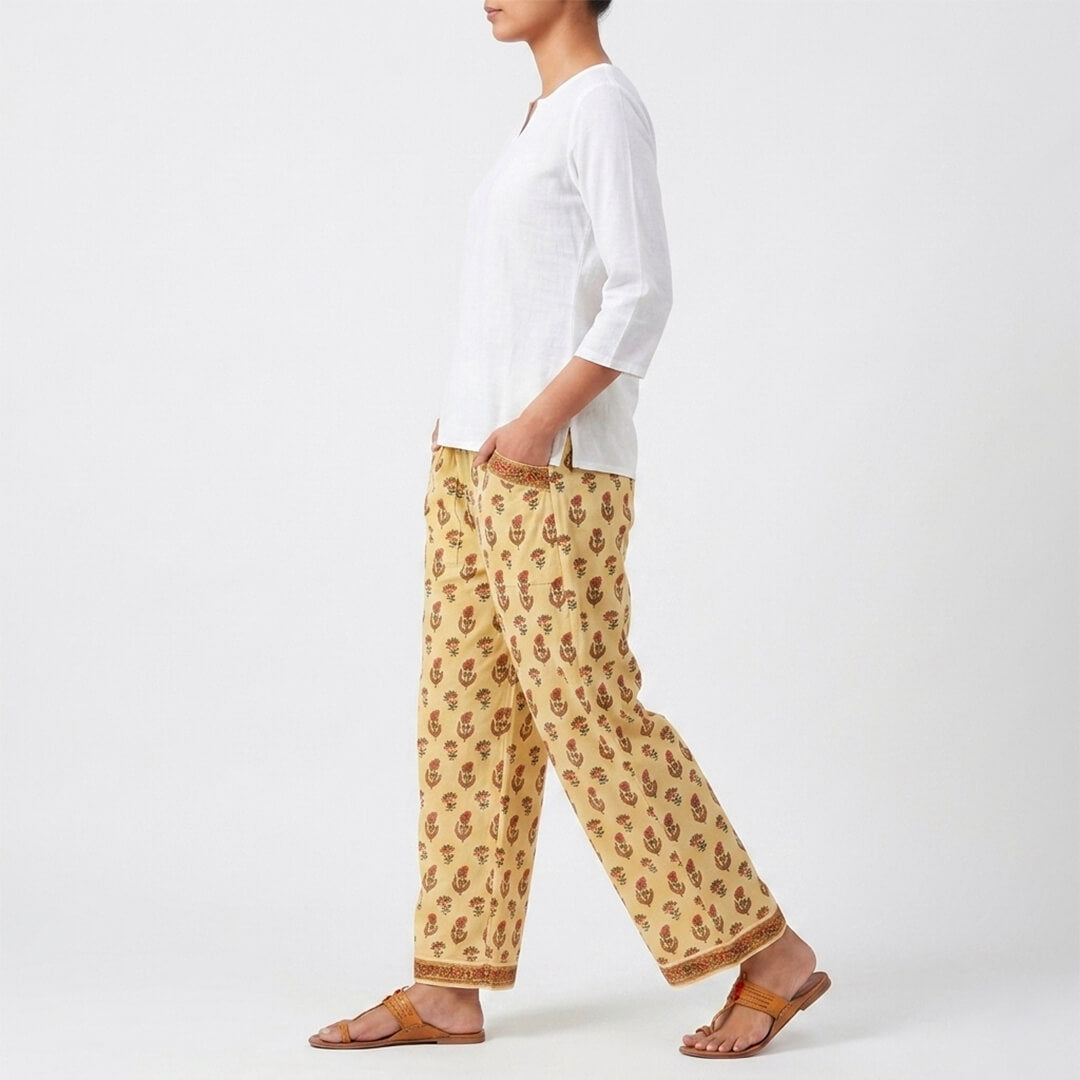 Person wearing a white shirt and patterned yellow pants on a white background