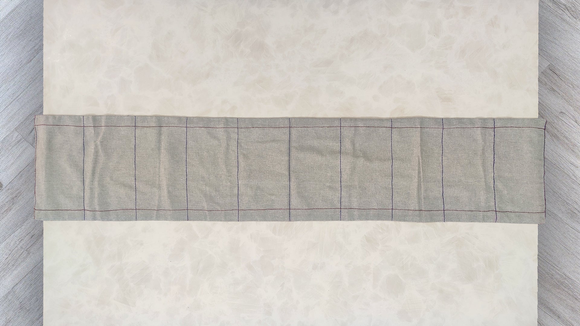 Hand embroidered with maroon and blue cotton thread, this handcrafted table runner is designed to be double sided.