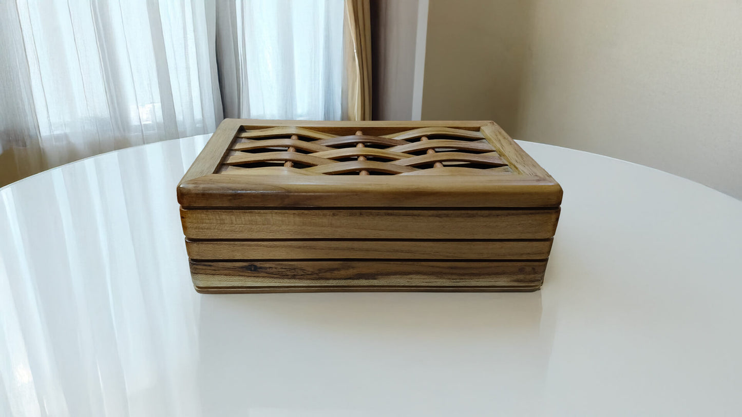 Wooden decorative box on a white surface with a light curtain background