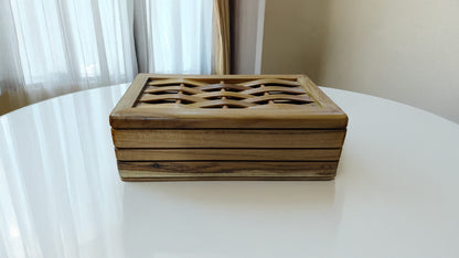 Wooden decorative box on a white surface with a light curtain background