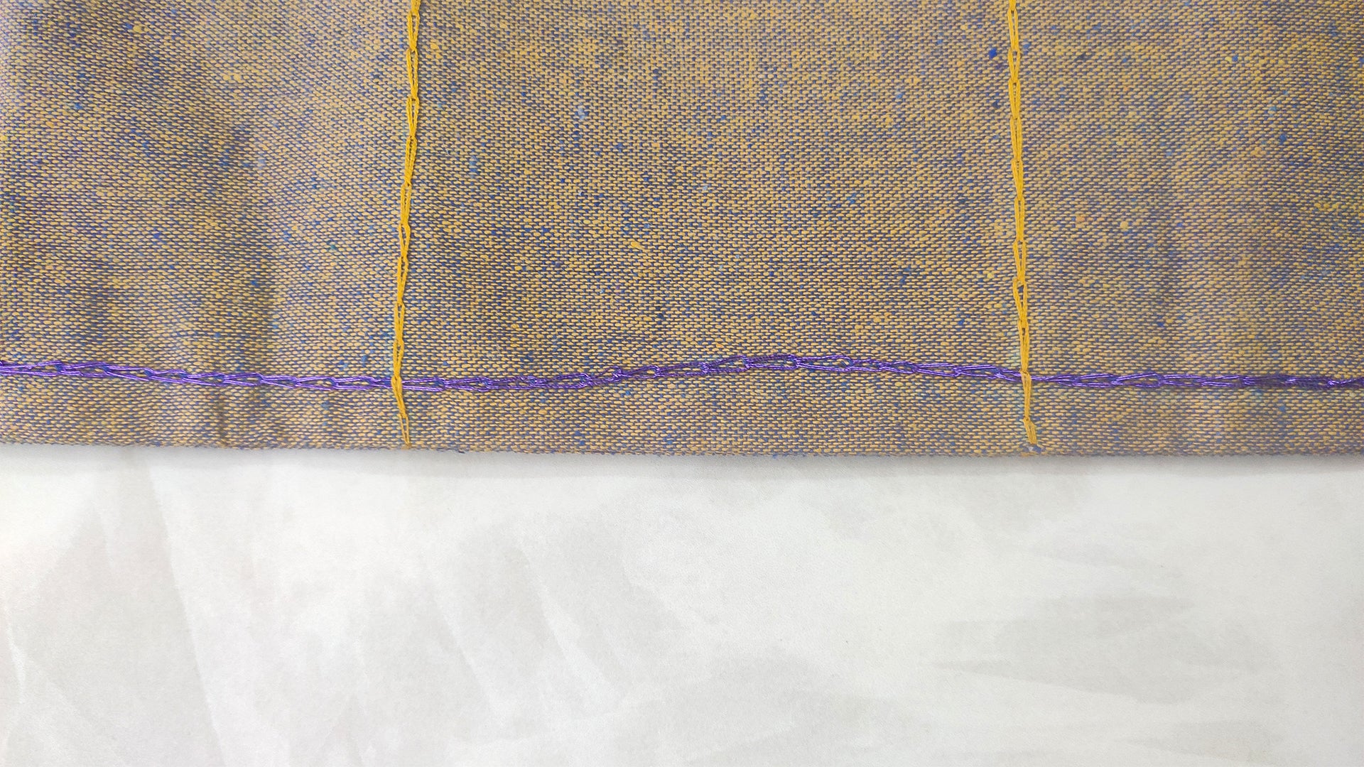 Hand embroidered with yellow and blue cotton thread, this handcrafted table runner is designed to be double sided.