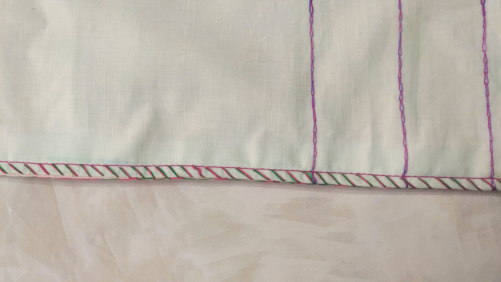 Hand embroidered with pink and purple cotton thread with golden zari, this handcrafted table runner is paired with set of 6 lap napkins. Designed to be double sided.